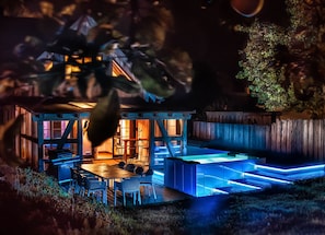 Une maison en bois avec un coin repas et un espace extérieur illuminé de lumière bleue.