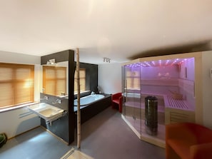 Une salle de bain moderne dotée d’une baignoire, d’un espace douche et d’un sauna à parois de verre.