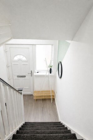 Een trap die leidt naar een kamer met een witte deur, een raam met uitzicht en een spiegel aan de muur.