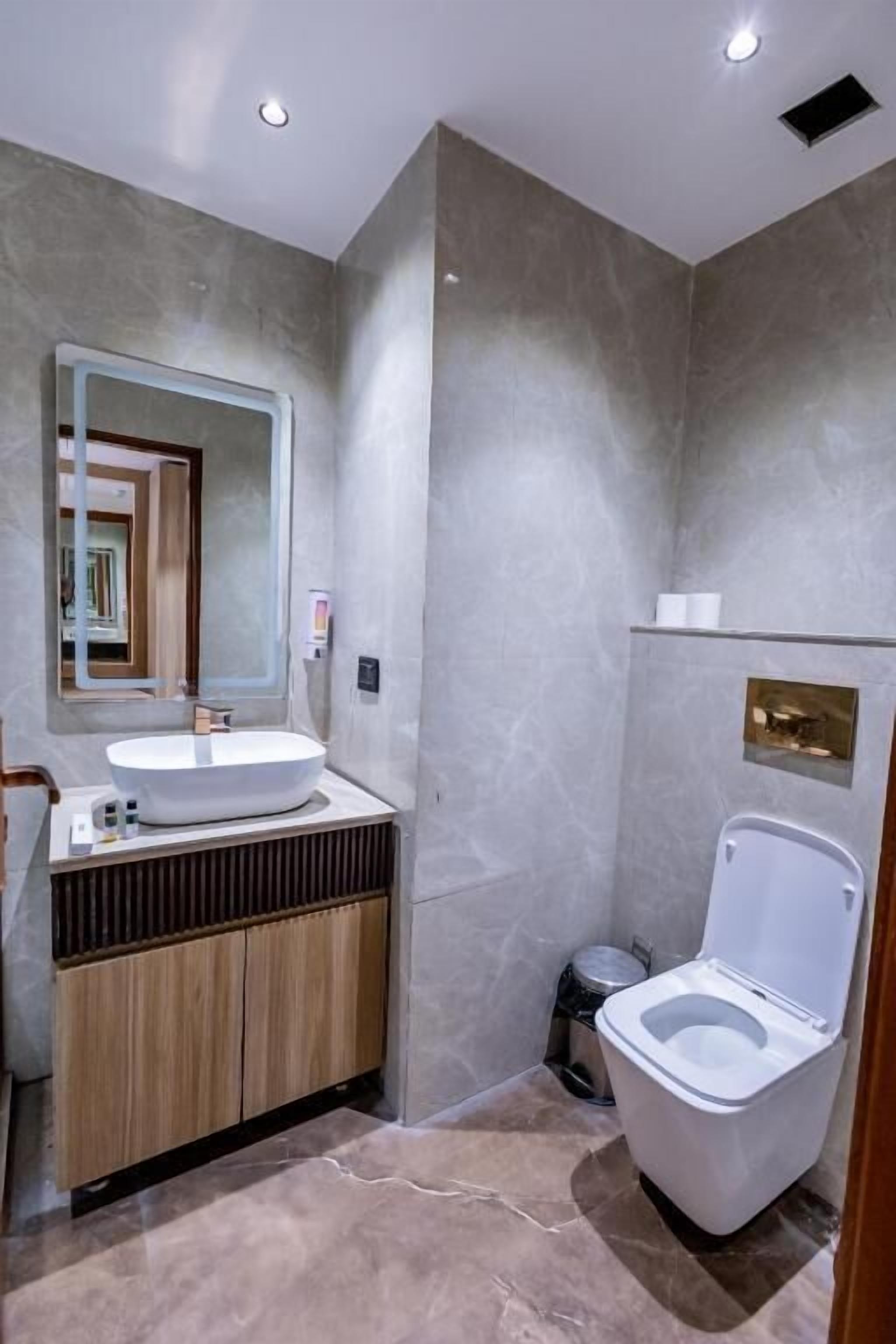 Un baño moderno con lavamanos, espejo, inodoro y tocador.