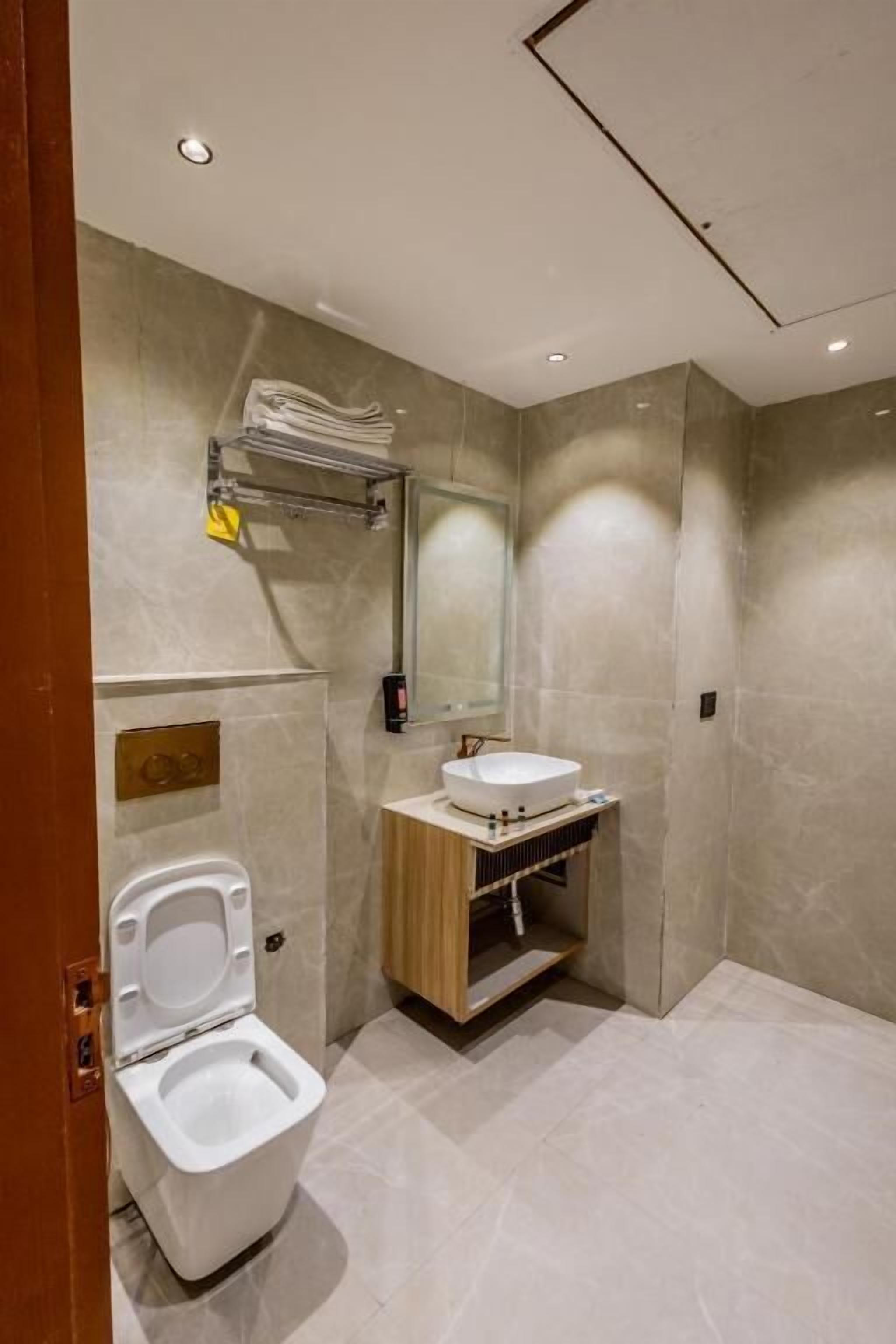 A modern bathroom with a toilet, sink, and mirror.