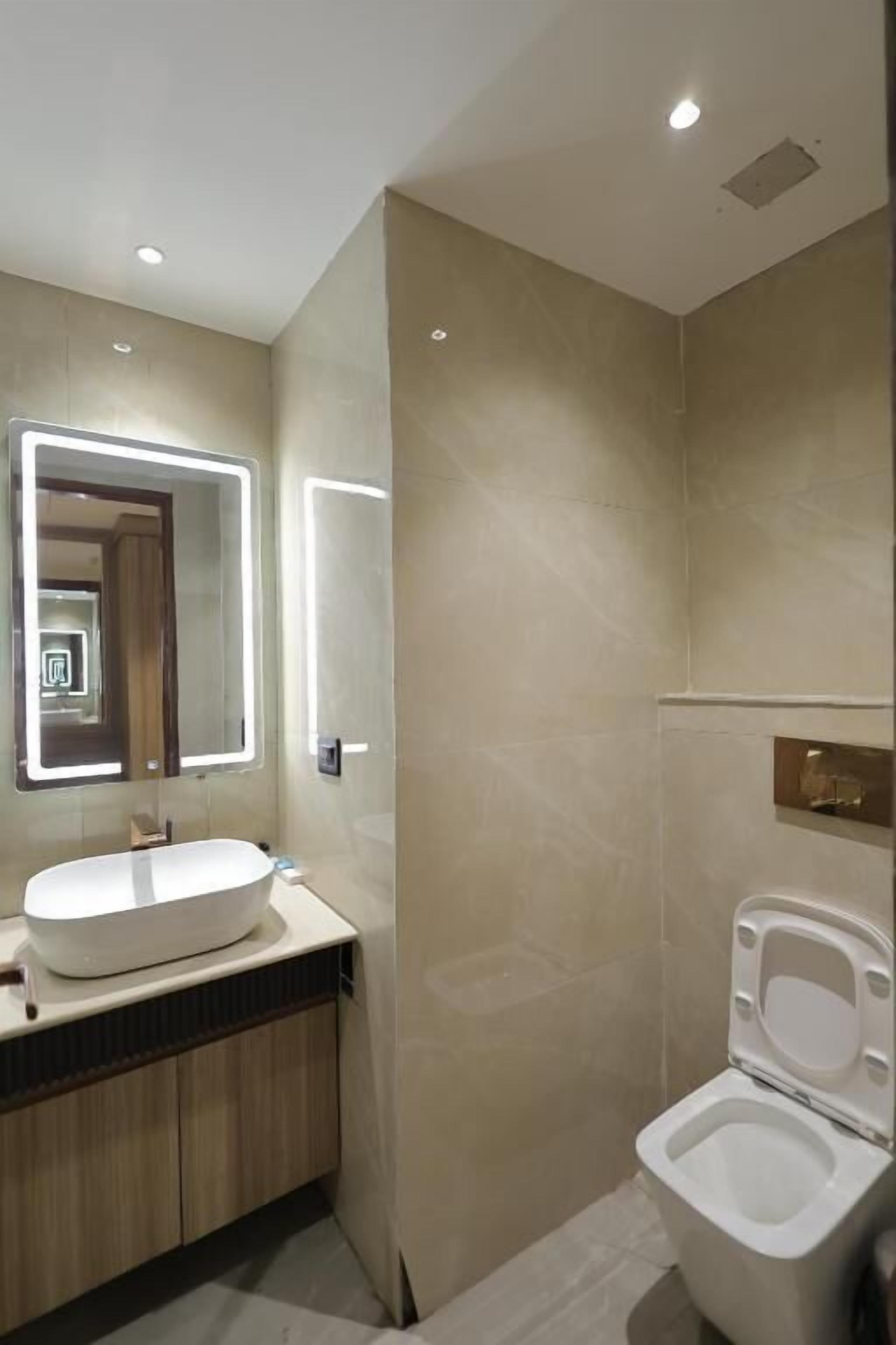 A modern bathroom with a large mirror, a sink, and a toilet.