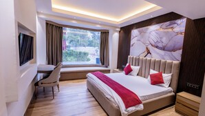 Una habitación de hotel moderna con una cama grande, un escritorio y una ventana con vistas a zonas verdes.