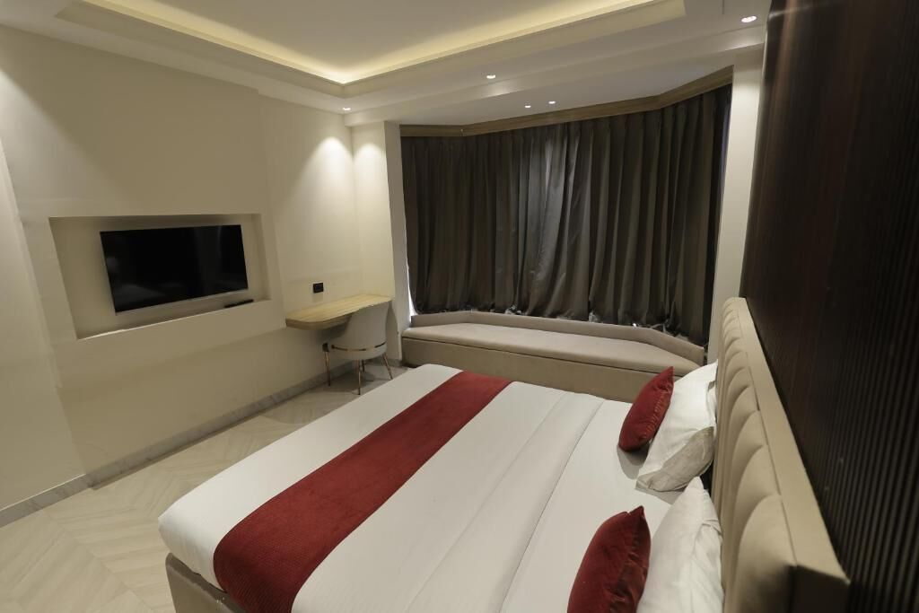 Una camera d'albergo moderna con un letto grande, una televisione a muro, una piccola scrivania e una finestra con tende.