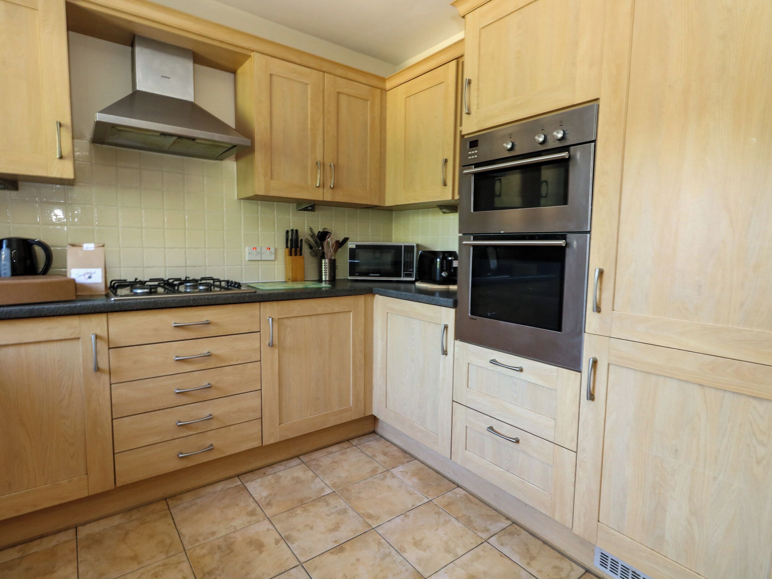 A kitchen with wooden cabinets, a gas stove, a microwave, and an oven.