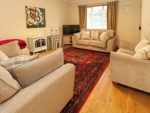 A living room with two sofas, a TV, a decorative rug, and a painting on the wall. - Fairways House (Weymouth)