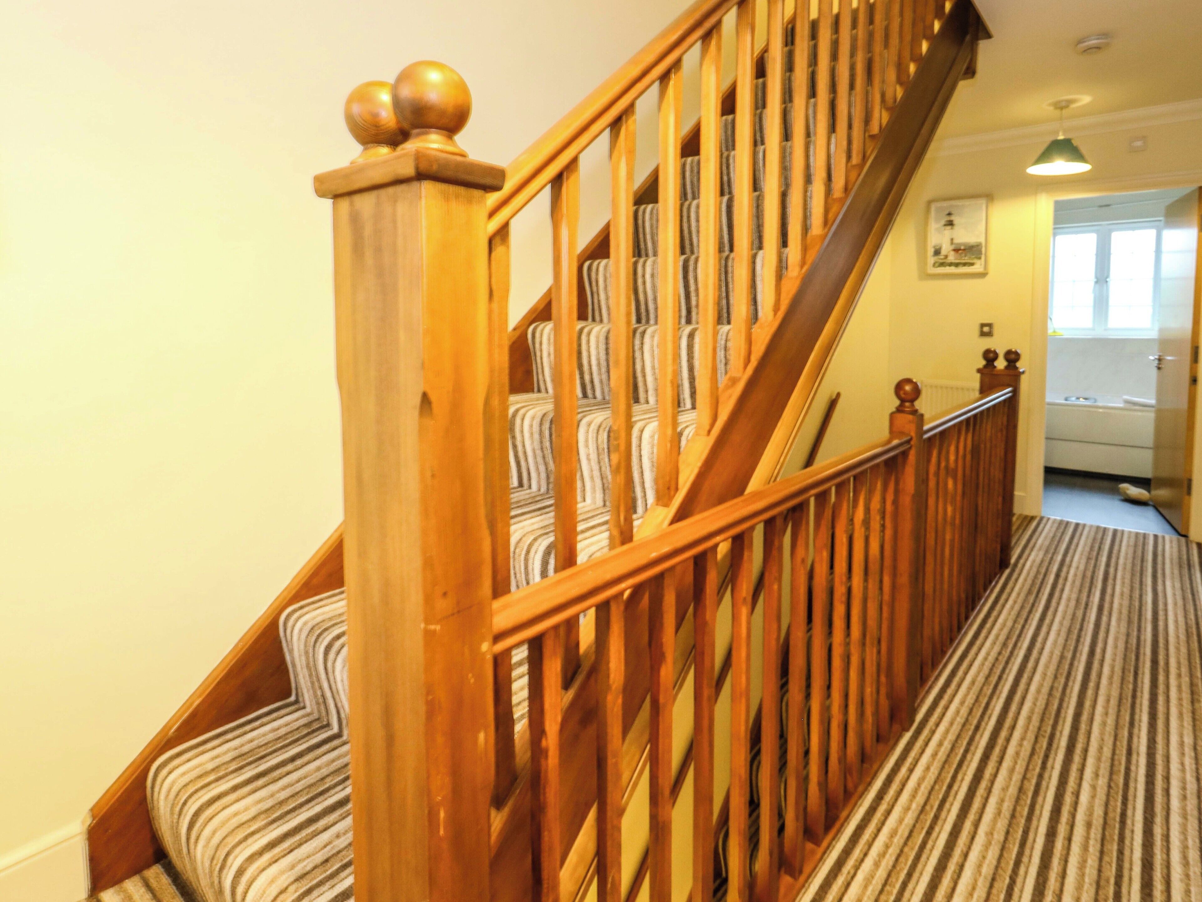 Eine Holztreppe mit Streifenmuster, einem Holnänder und einem Bild an der Wand.