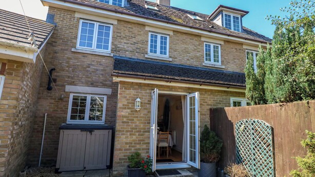 Une maison à deux étages avec une façade en briques, un toit en tuiles et une clôture en bois.