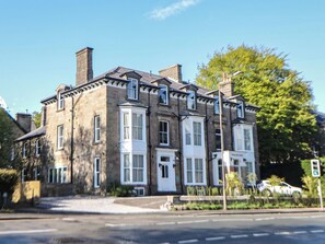 A multi-story building with a symmetrical facade, large windows, and a prominent chimney. - The Devonshire Suite (Buxton)