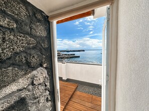A balcony with a view of the sea and a wooden deck. - Pico Island Villas 2 · Oceanfront Retreat (Cais do Pico)