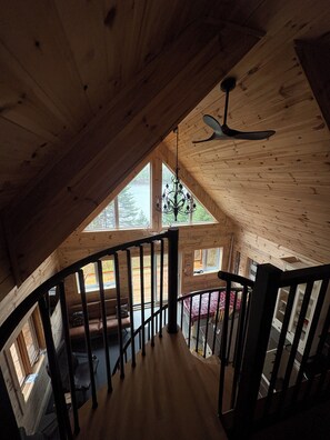 Ein Holzinnenraum mit Treppe, Deckenventilator und großen Fenstern.