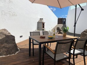 Ein Essbereich im Freien mit Tisch, Stühlen und einem großen Sonnenschirm.
