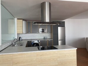 Eine moderne Küche mit Einbauwaschmaschine, Edelstahlgeräten und einer großen Kochinsel.
