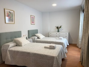 Ein Hotelzimmer mit zwei Betten, einem Nachttisch und einem Fenster mit Vorhängen.