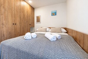 Ein Hotelzimmer mit Bett, Holzschrank und einem Gemälde an der Wand.
