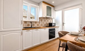 Eine moderne Küche mit weißen Schränken, einer Holz Arbeitsplatte und einem Essbereich mit Tisch und Stühlen.
