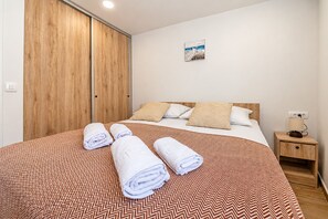 Een hotelkamer met een bed, een nachtkastje, een houten garderobe en een aan de muur hangend schilderij.