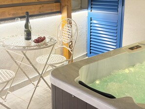 Eine Sitzecke mit Whirlpool, einem Tisch, einer Flasche und Gläsern.
