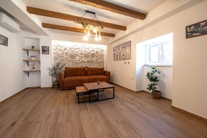 Una sala acogedora con un sofá marrón, una mesa de centro y una pared de piedra.