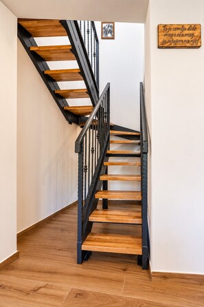 Eine Holztreppe mit schwarzen Geländern, die zu einer oberen Etage führt.