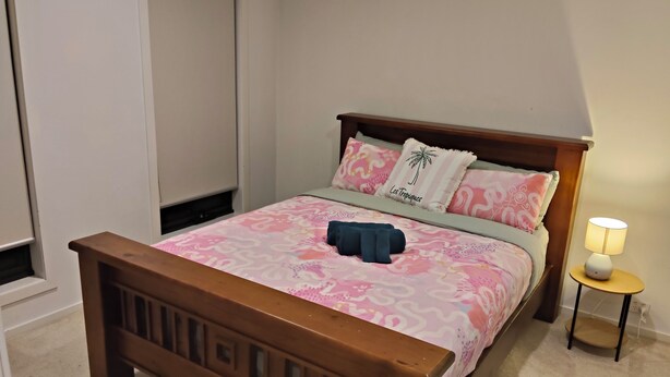 Um quarto com estrutura de cama de madeira, colcha estampada e abajur.
