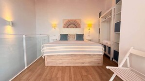 A bedroom with a bed, bedside lamps, a wall-mounted artwork, and a wooden ceiling. - Gerona Luxury Apartments (Seville)