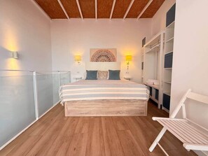 A bedroom with a bed, bedside lamps, a wall-mounted artwork, and a wooden ceiling. - Gerona Luxury Apartments (Seville)
