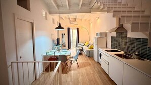 A modern kitchen with white cabinets, a dining area with a table and chairs, and a staircase leading to an upper level. - Gerona Luxury Apartments (Seville)