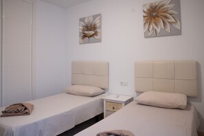 A hotel room with two beds, a nightstand, and artwork on the wall. - Sara 5, Playa Blanca (Playa Blanca)