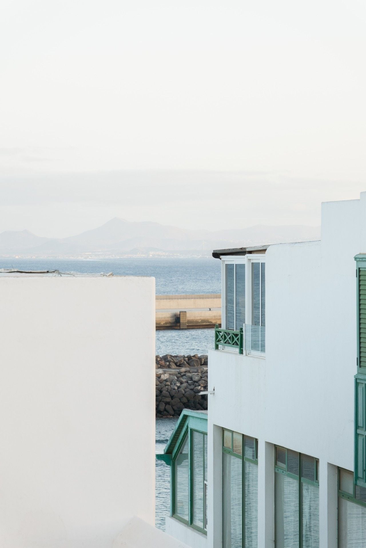 A coastal building with a view of the sea and distant mountains.