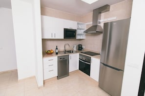 A modern kitchen with white cabinets, a stainless steel refrigerator, a dishwasher, a stove, and a microwave. - Sara 5, Playa Blanca (Playa Blanca)