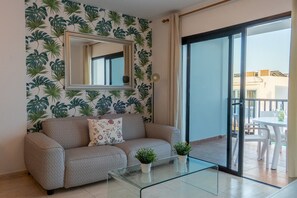 A living room with a sofa, a glass coffee table, a mirror, and a balcony with outdoor furniture. - Sara 5, Playa Blanca (Playa Blanca)