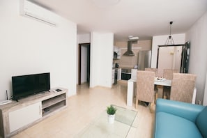 A modern living room with a flat-screen TV, a sofa, a dining area with chairs, and a kitchen in the background. - Sara 5, Playa Blanca (Playa Blanca)