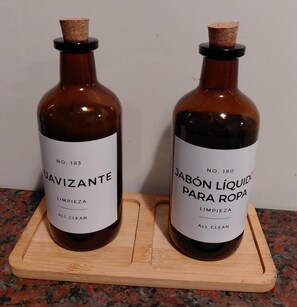 Two bottles of cleaning products on a wooden board. - Suite Bravo - 2-Bedroom Apartment in Almagro (Buenos Aires)