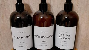 Kolme pulloa shampoota, hoitoainetta ja suihkugeeliä puisella hyllyllä.