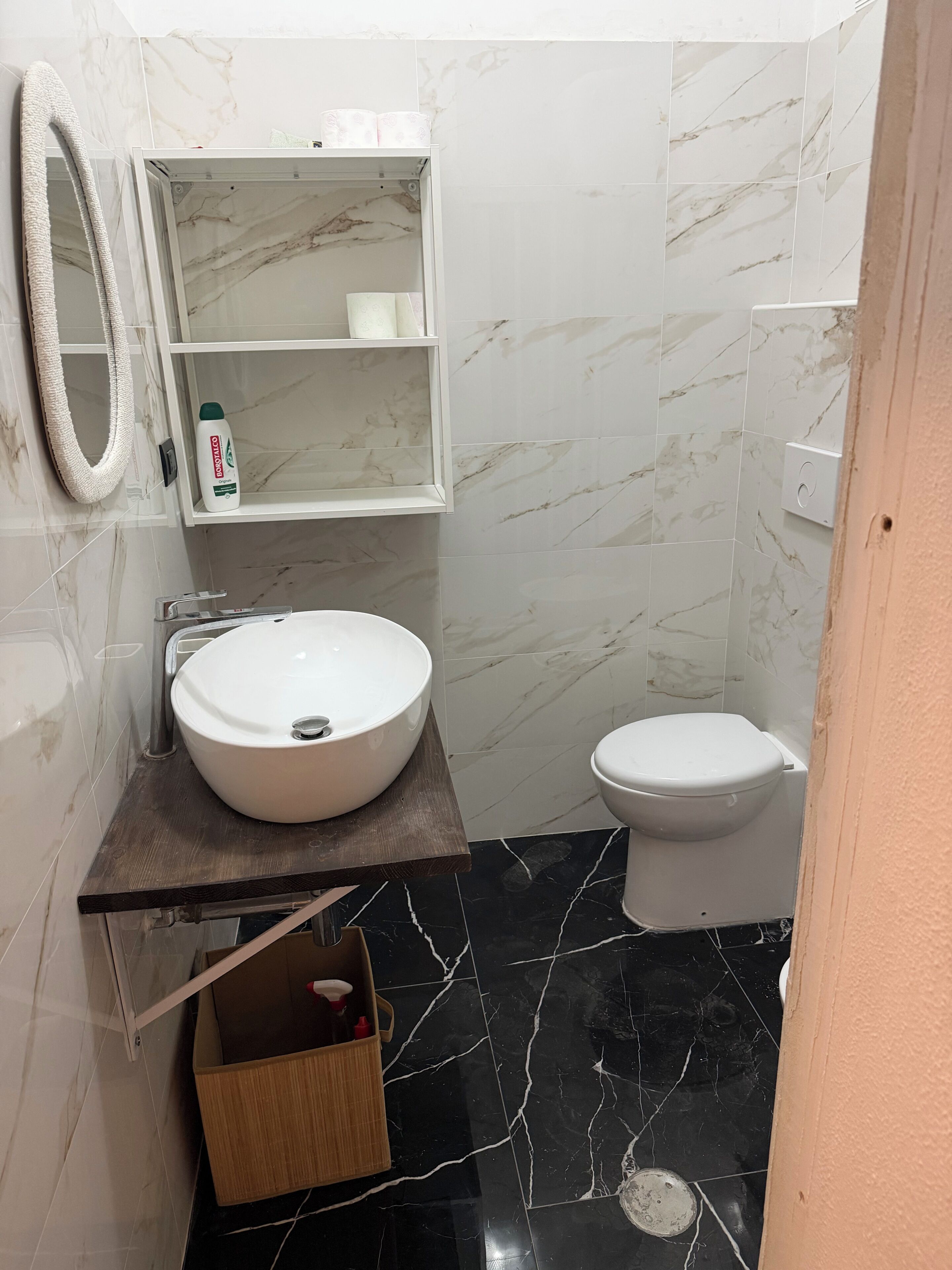Une salle de bain avec un lavabo blanc, des toilettes et un miroir.