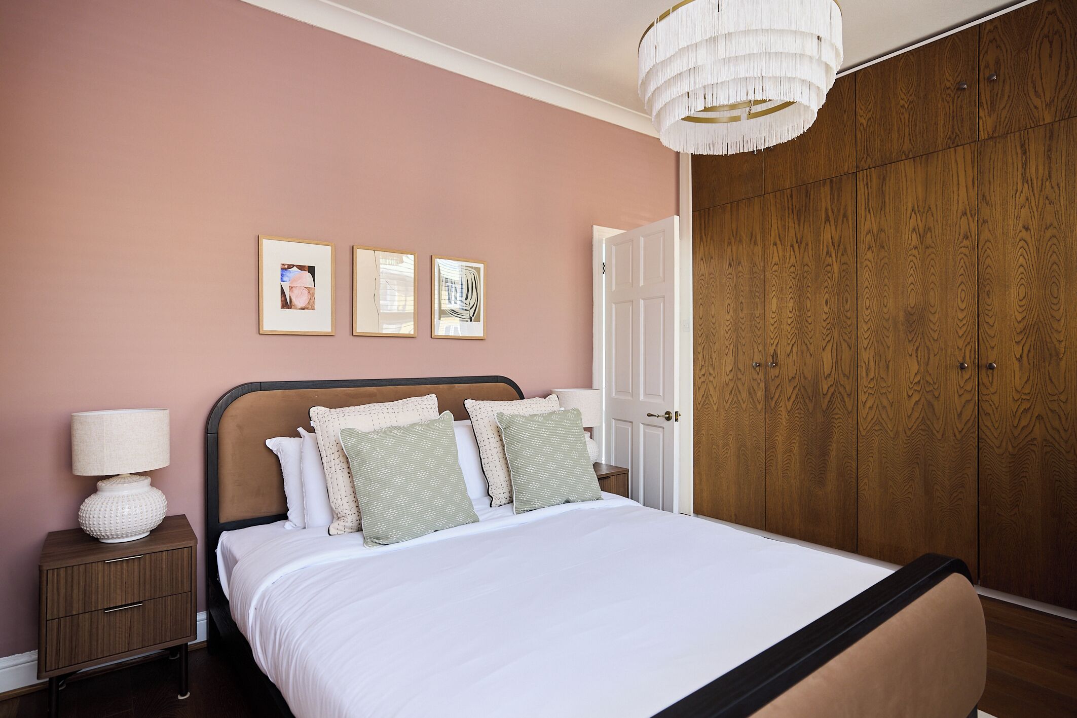 Une chambre à coucher comprenant un lit, une table de chevet, une lampe et une œuvre d’art accrochée au mur.