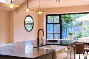 A modern kitchen with a central island, pendant lighting, a large window, and a view of the outdoors. - The Cobalt & Olive Terrace - Peckham (London)