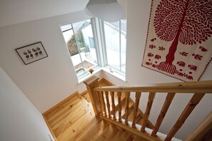 A wooden staircase with a view of a garden through a window.