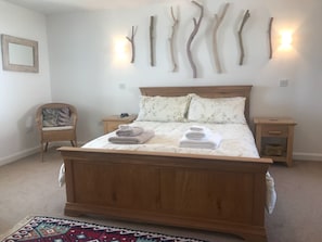 Une chambre à coucher avec un lit en bois, deux tables de chevet, une chaise et des branches fixées au mur.