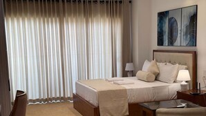 A hotel room with a bed, bedside tables, a desk, and a chair.