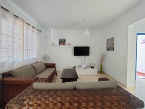 Ein Wohnzimmer mit einer Couch, einem Couchtisch, einem Flachbildfernseher und einem weißen Schrank.