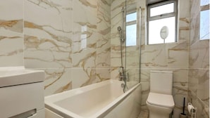 Een badkamer met bad, toilet en een douchecabine.