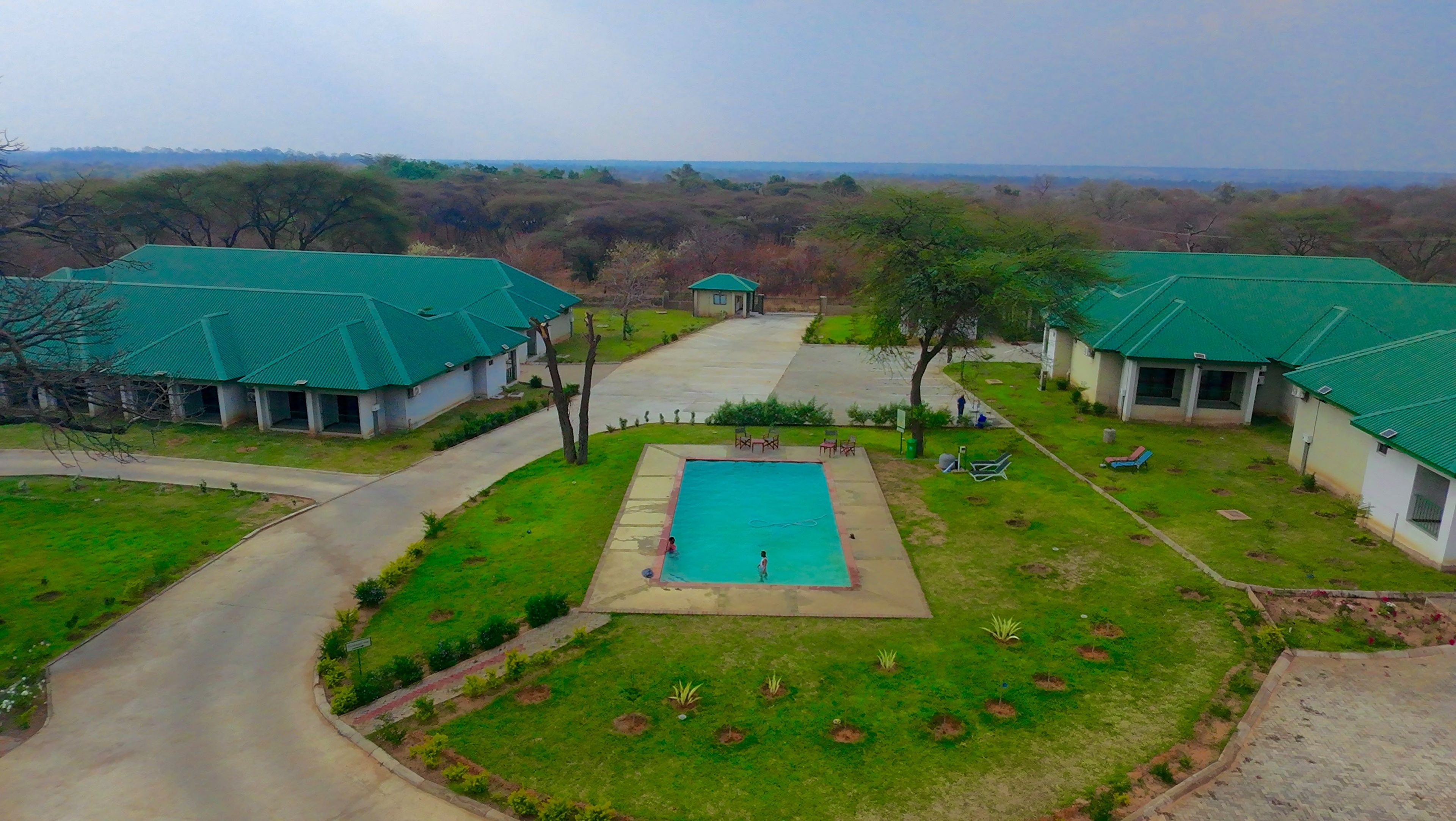 A residential area with a swimming pool, green-roofed houses, and a clear view of the surrounding landscape.