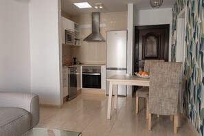 A modern kitchen with stainless steel appliances, a dining table with chairs, and a patterned wall. - Sara 3, Playa Blanca (Playa Blanca)