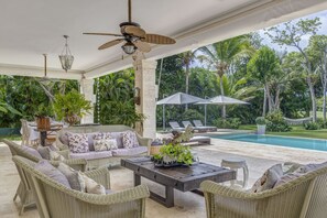 An outdoor patio with wicker furniture, a pool, and lush greenery. - Villa Golf & Sun Retreat (Adeje)