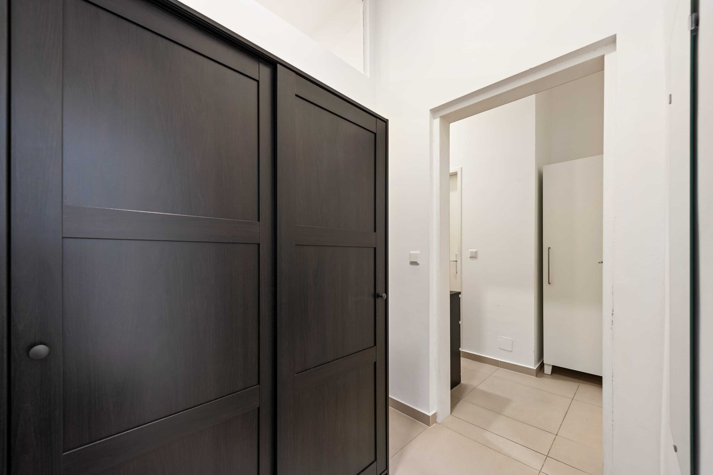 A hallway with dark wooden doors and white walls.