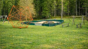 Eine geometrische Metallkonstruktion in einem grasbewachsen Feld, im Hintergrund Bäume.