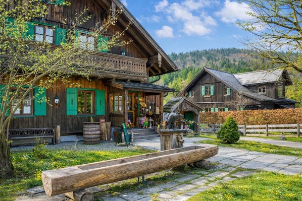 A traditional wooden building with a balcony, a wooden bench, and a stone pathway.