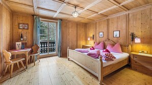 A wooden-paneled room with a bed, a desk, and a chair.